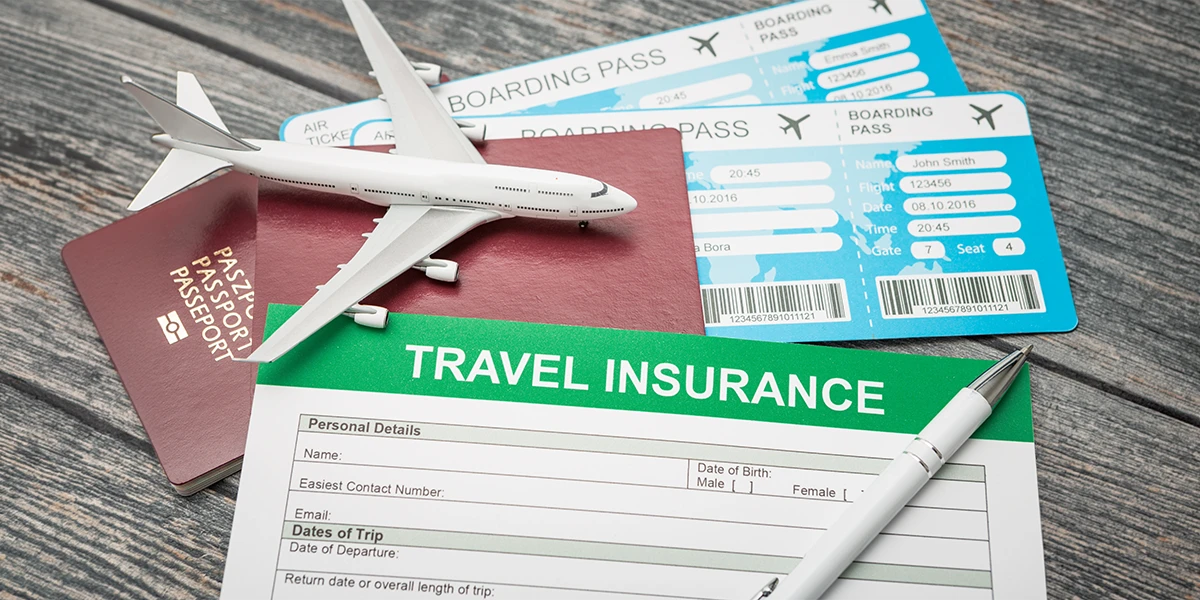 A travel insurance application form on a wooden desk next to a model airplane, passports, and boarding passes, highlighting the importance of Business Travel Insurance for International Trips.