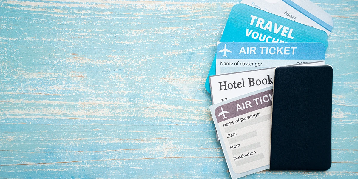 A collection of air tickets, hotel booking confirmations, and travel vouchers representing all-inclusive travel packages from Abu Dhabi arranged on a blue wooden surface.