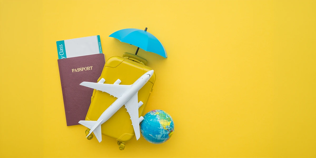Passport, airplane model, suitcase, globe, and umbrella symbolizing travel insurance coverage for safe and protected international travel.