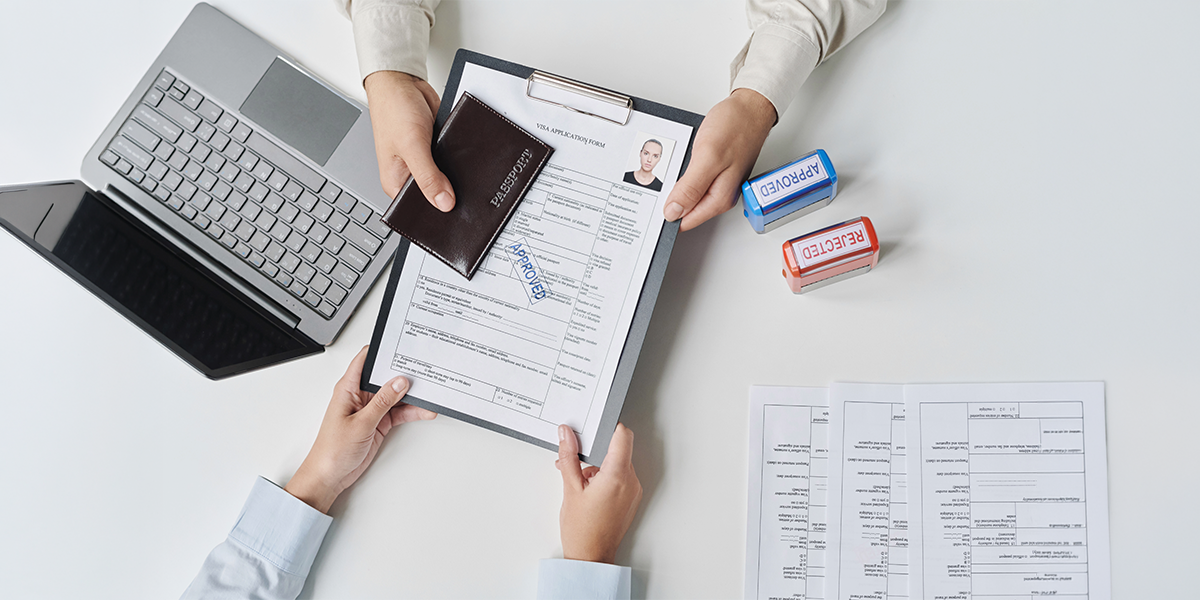 Tourist and visa specialist reviewing a visa application form with a passport and approved visa stamps on a desk.