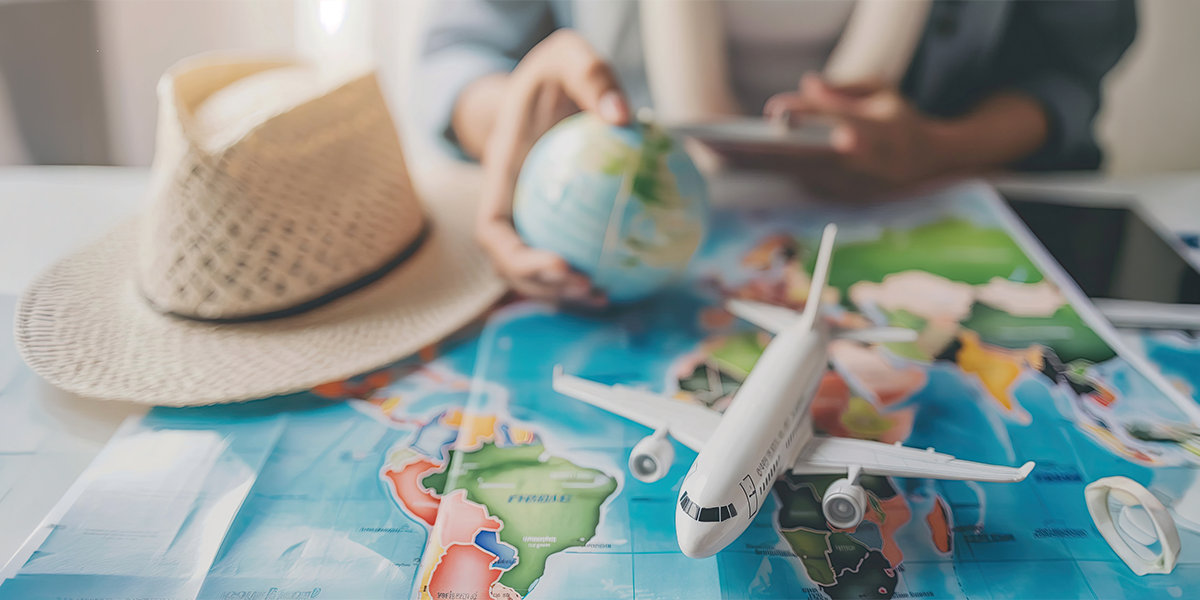 Travel planning with a world map, toy airplane, globe, and travel accessories on a table.